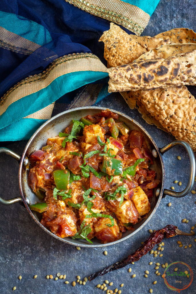 Served Kadai Paneer in Indian wok with papad on the side.