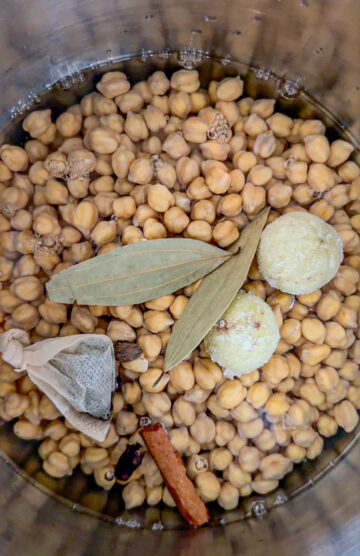 Chickpeas cooking with tea bag and whole spices in a pot.