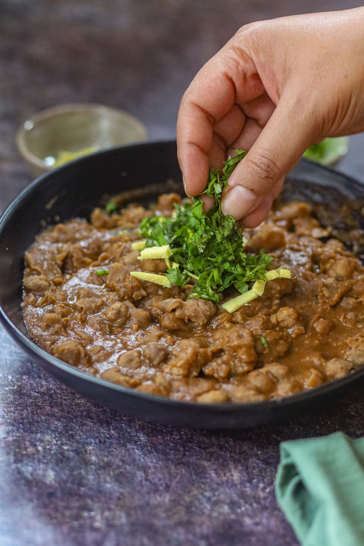 Garnishing Delhi style chole with fresh cilantro and ginger.