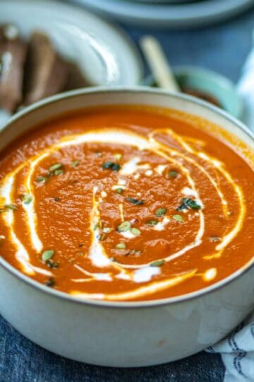 Overhead closeup shot of dairy-free tomato soup in a white bowl which is garnished.