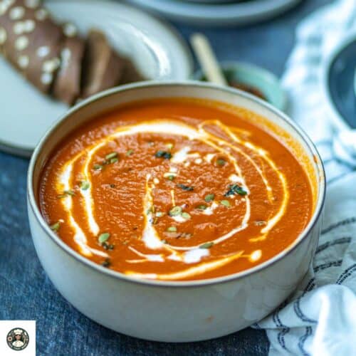 Overhead closeup shot of dairy-free tomato soup in a white bowl which is garnished.
