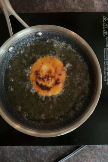 Aloo tikki deep frying in hot oil until golden.