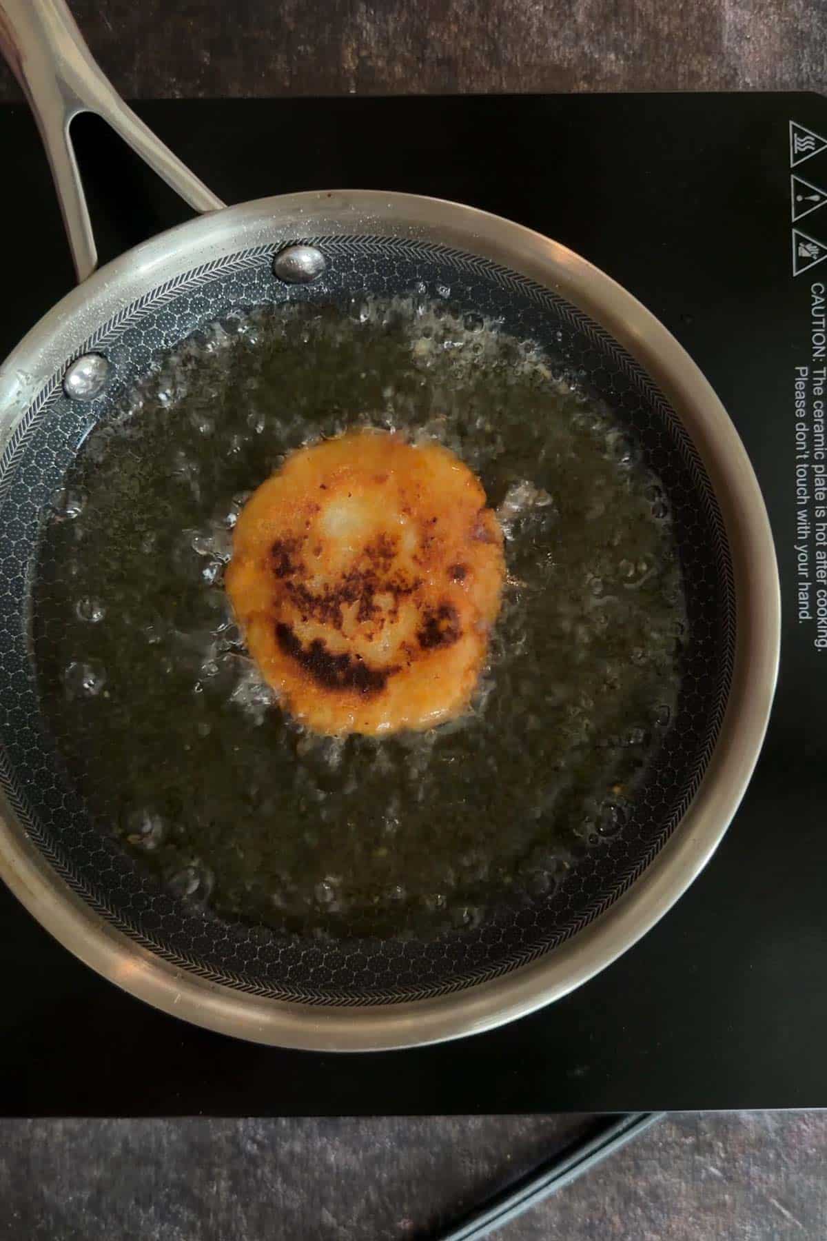 Aloo tikki deep frying in hot oil until golden.