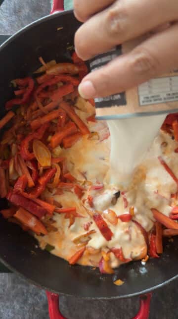 Pouring coconut milk into Thai red curry with vegetables.