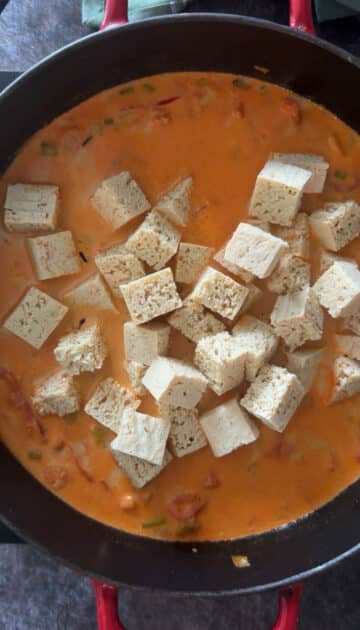 Adding cubed tofu to curry.