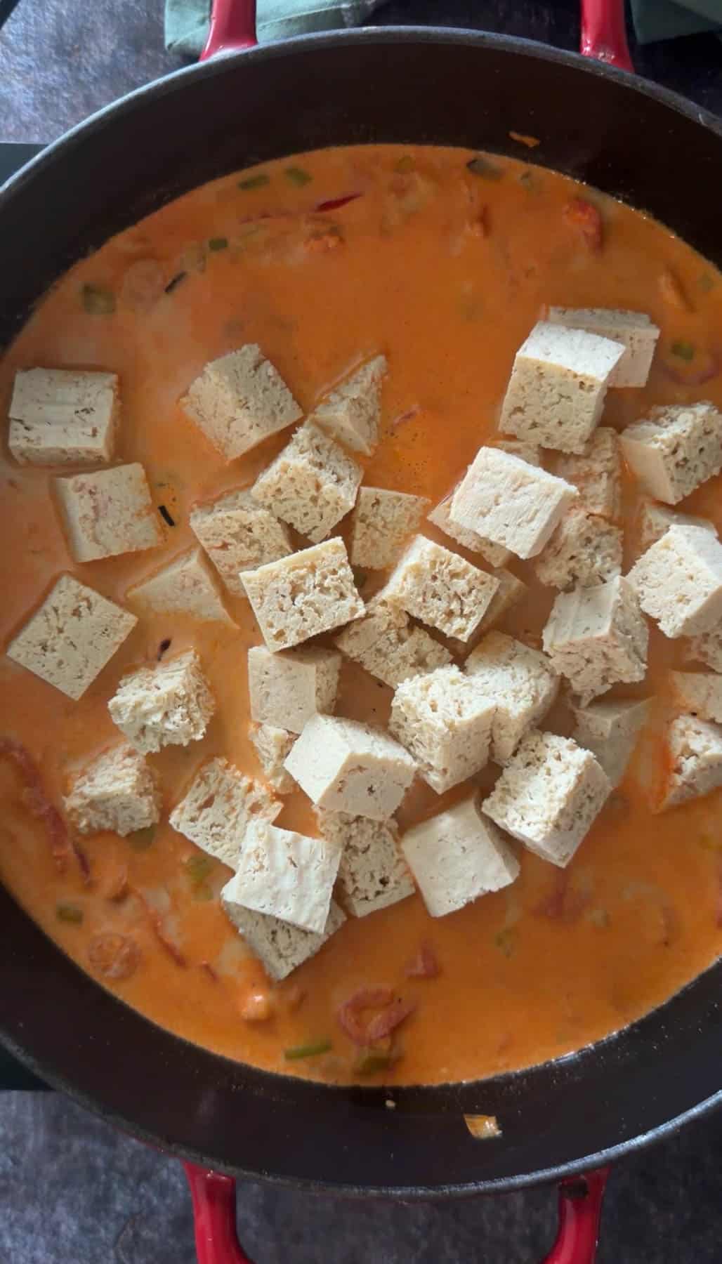Adding cubed tofu to curry.
