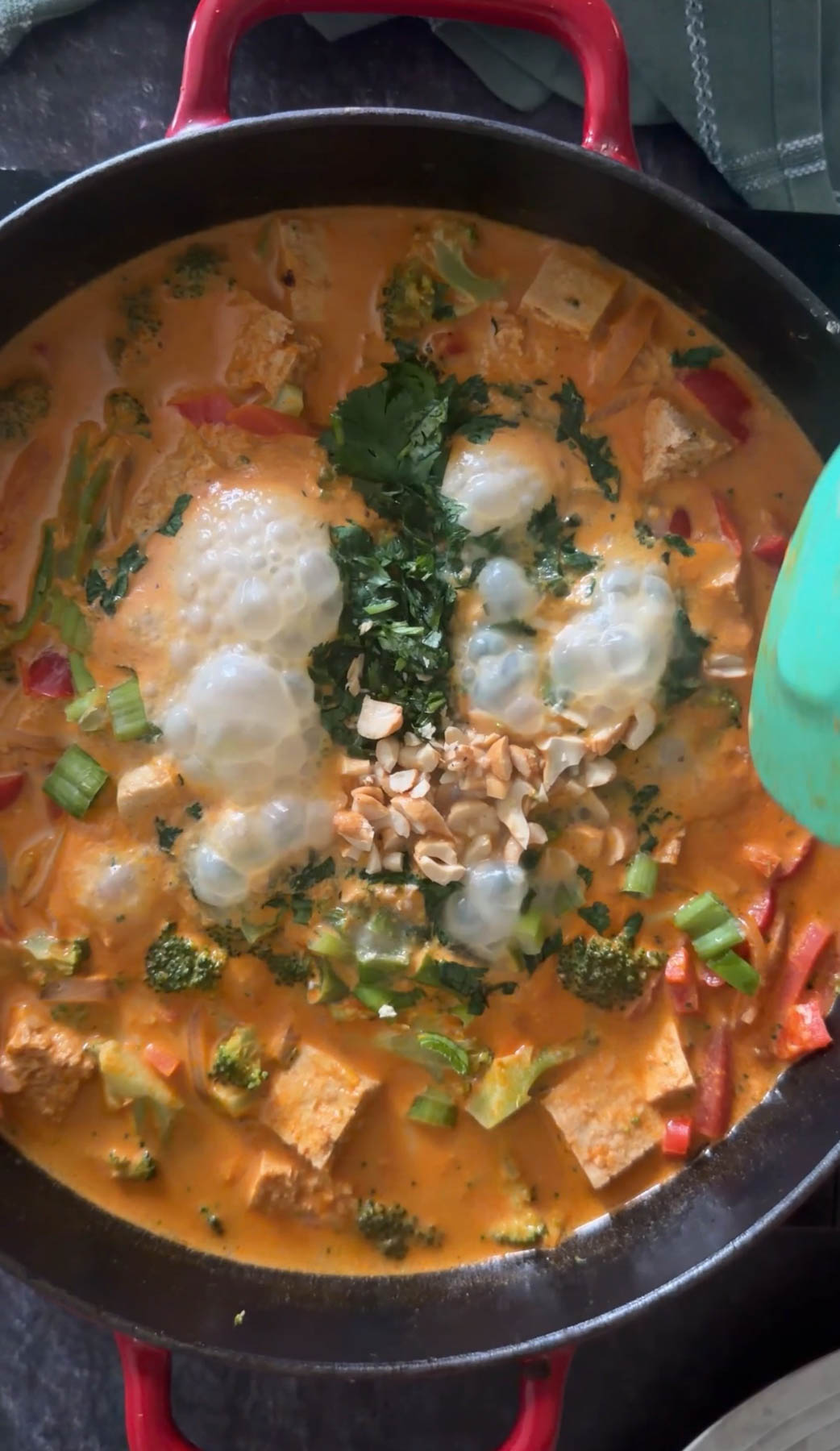 Garnishing Thai curry noodles with peanuts, cilantro, lime juice, and green onions.