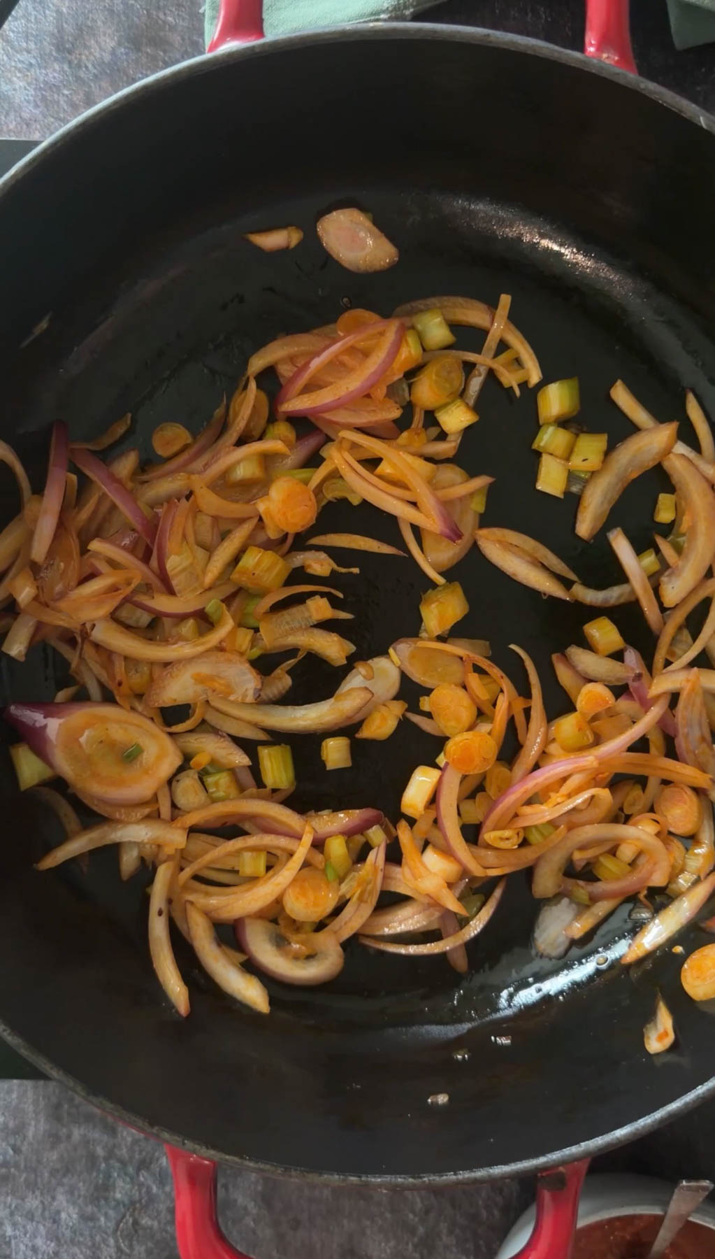 Sautéing onions, garlic, and green onions in chili oil.f