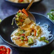 Creamy Thai curry noodles with tofu simmering in a rich coconut curry sauce with broccoli, bell peppers, and carrots.