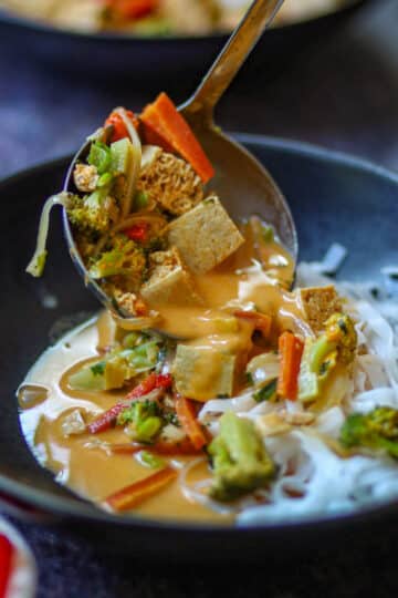 Creamy Thai curry noodles with tofu simmering in a rich coconut curry sauce with broccoli, bell peppers, and carrots.