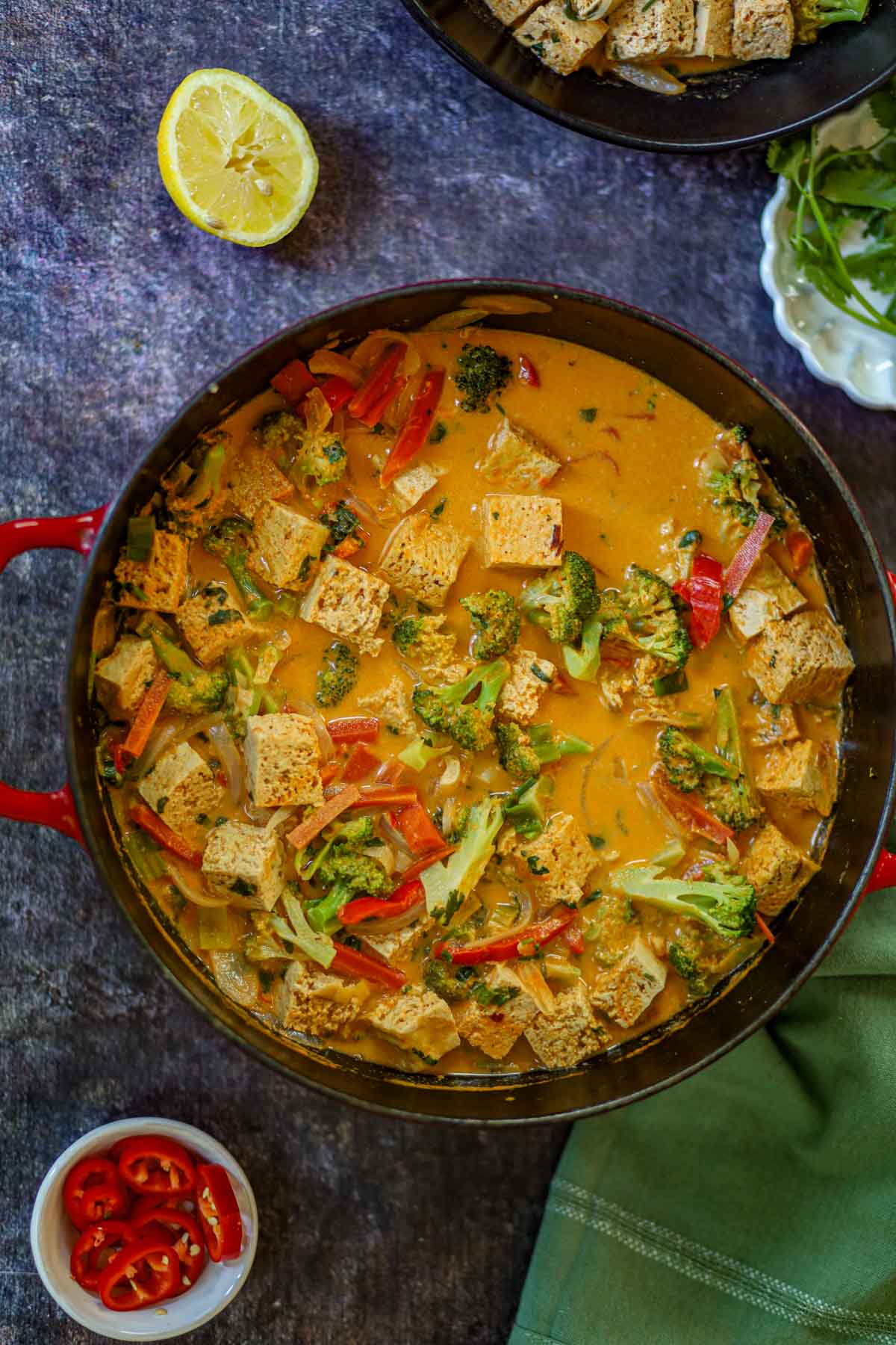 Creamy Thai red curry with tofu and vegetables cooking in a Dutch oven.