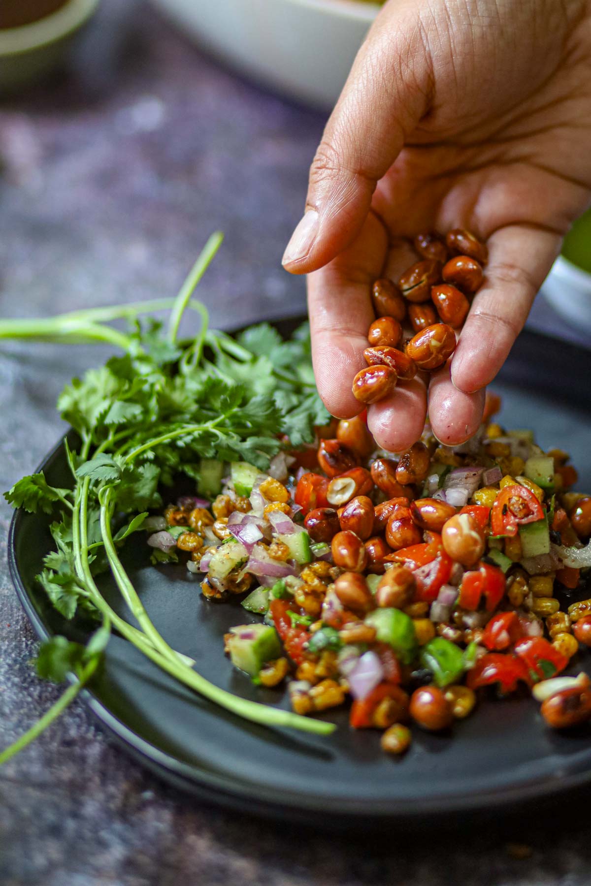 Roasted peanuts being added to corn chaat.