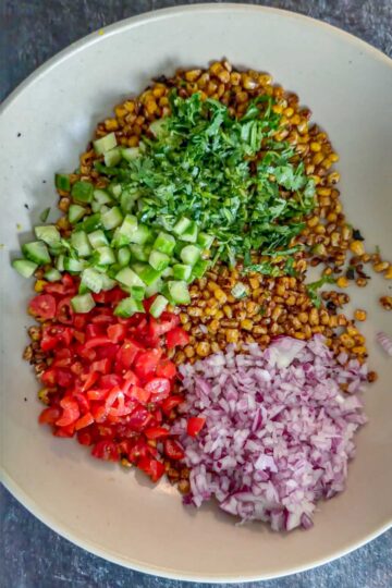 Chopped vegetables and cilantro added to charred corn.