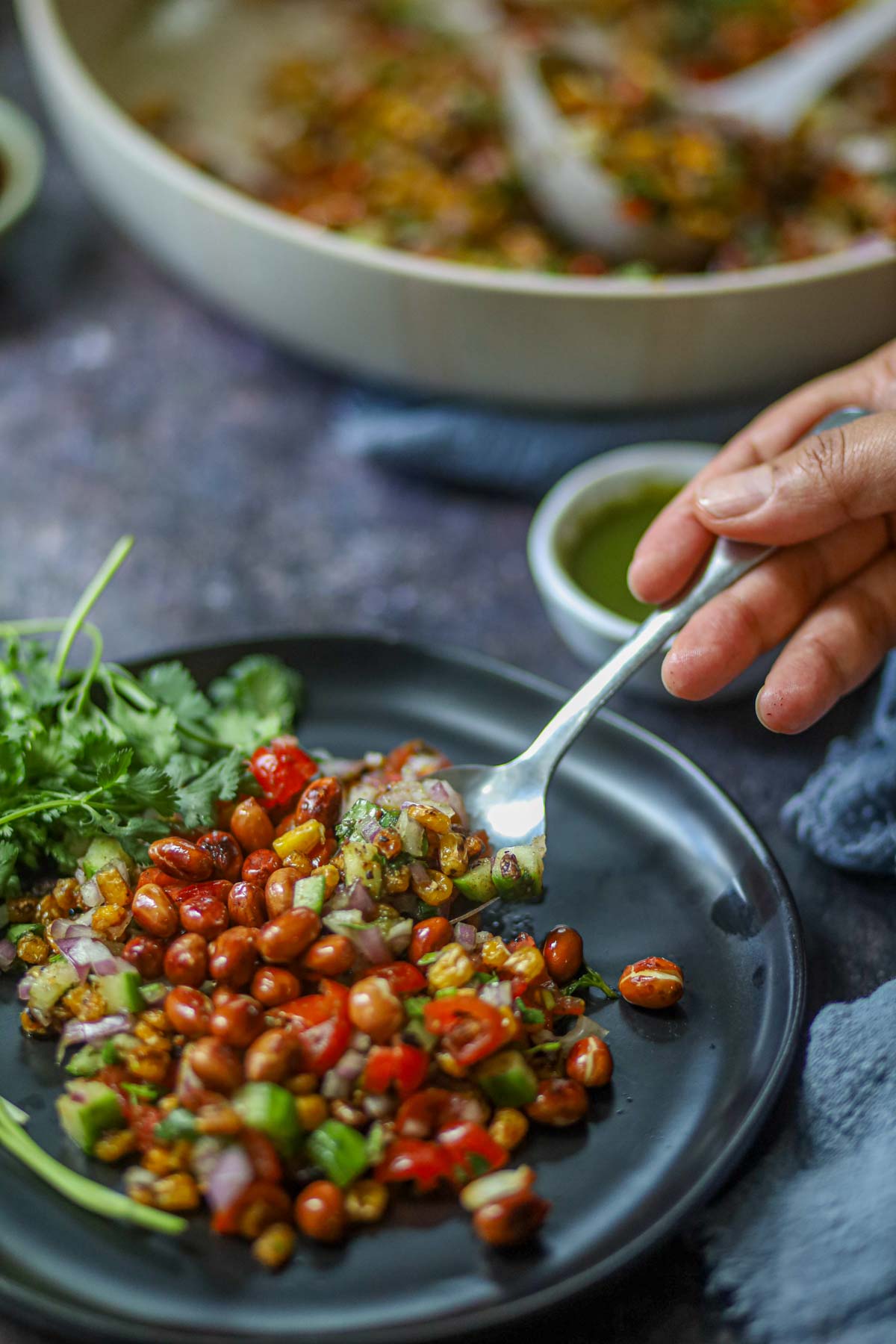 Street-style corn chaat being served with a spoon.