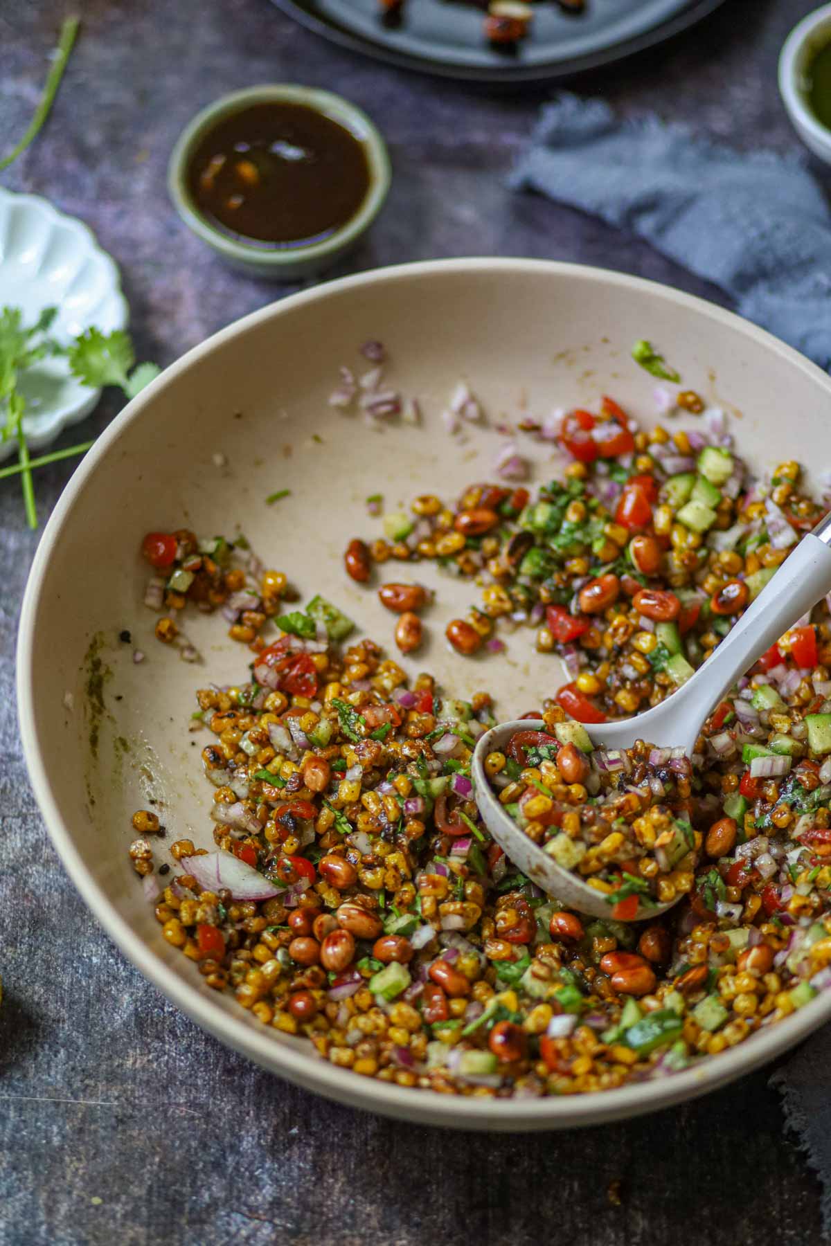 Spoonful of charred corn chaat with peanuts and vegetables.