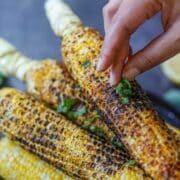 Garnishing Indian roasted corn with fresh cilantro.