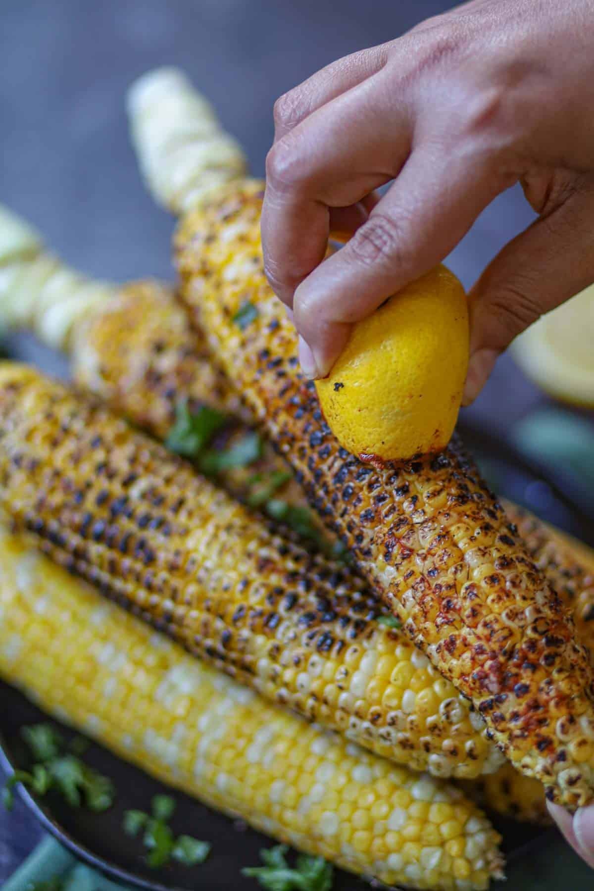 Rubbing lemon and bhutta masala over roasted corn.