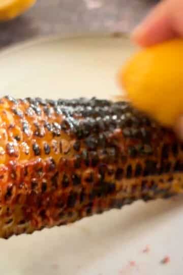 Rubbing lemon over charred Indian roasted corn.