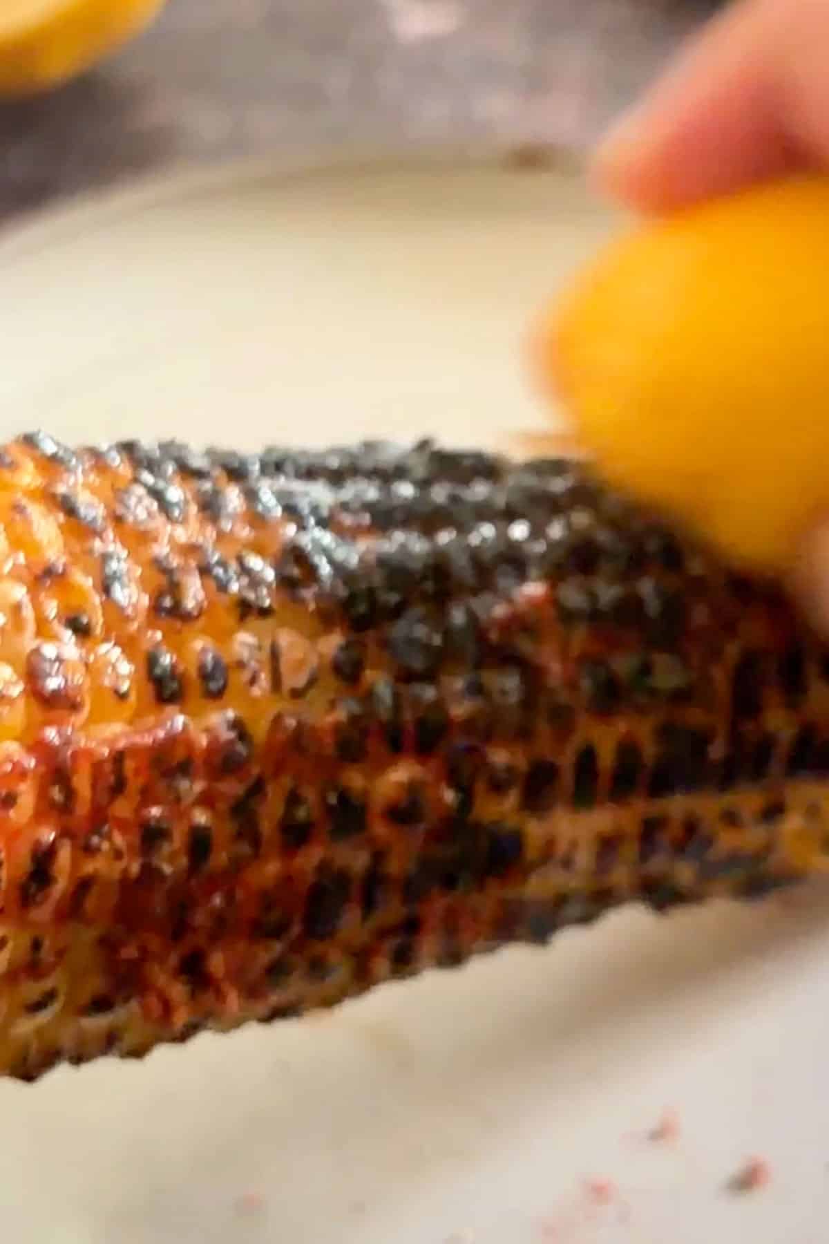 Rubbing lemon over charred Indian roasted corn.