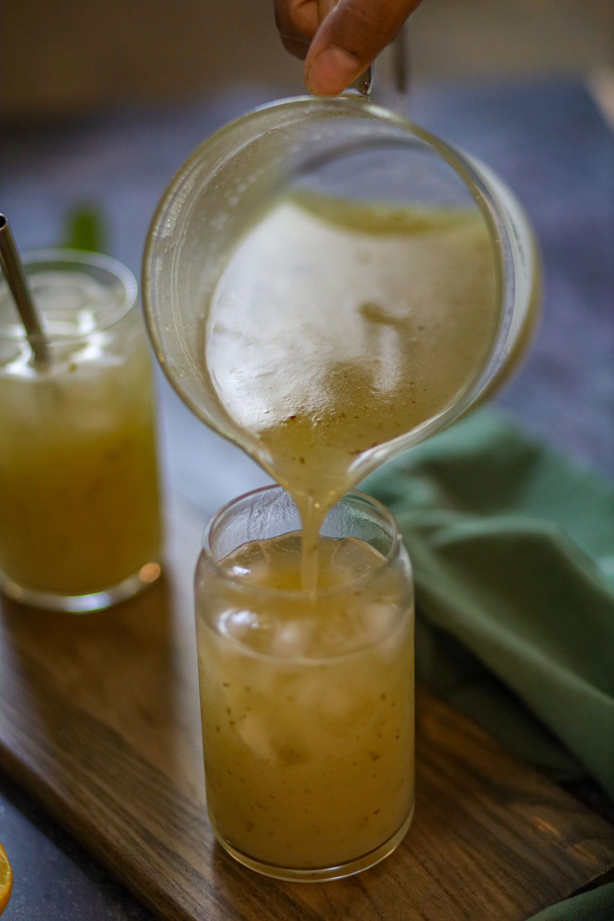 Aam panna being poured over ice into a glass.