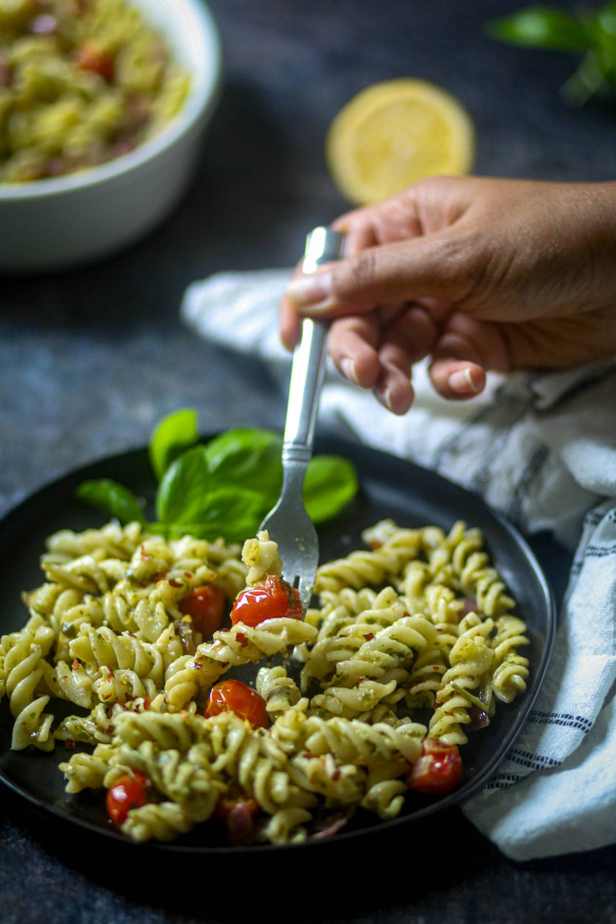 Picking a bite of vegan pesto pasta in a fork.