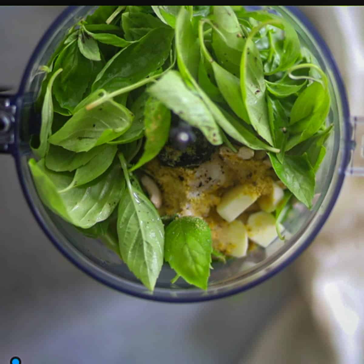 Add baisl leaves, olive oil, garlic, nutritional yeast, and cashews in a food processor.