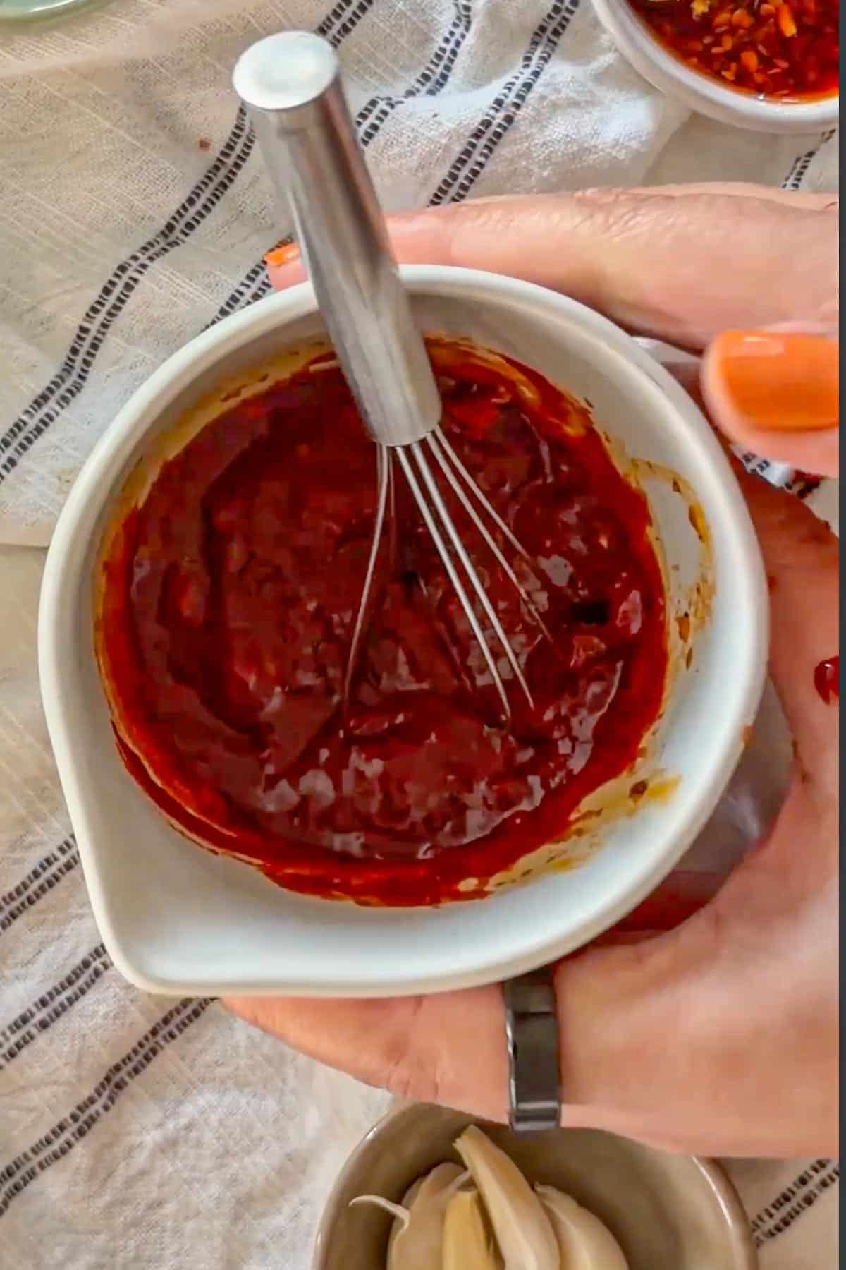 Whisking gochujang glaze in a bowl for roasting carrots.