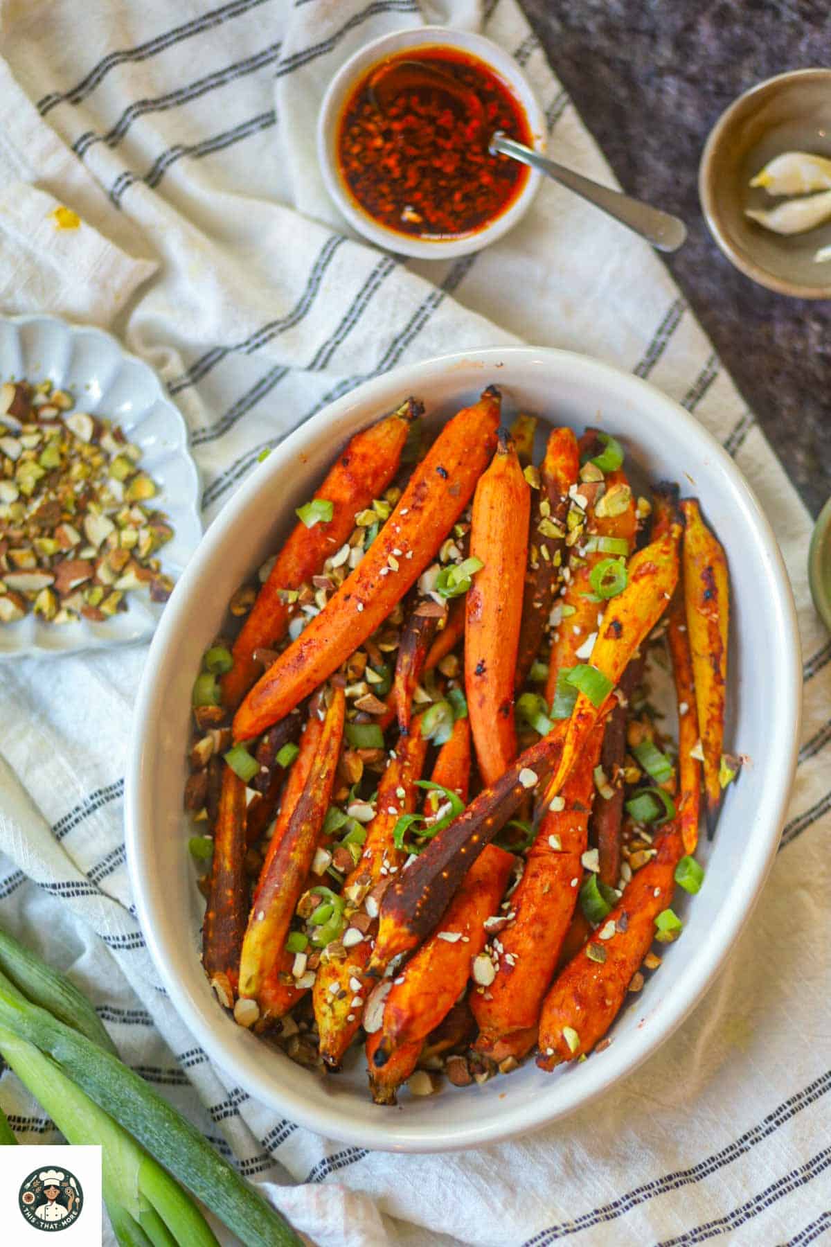 Top view of roasted gochujang carrots with spicy glaze, chopped nuts, and green onions.