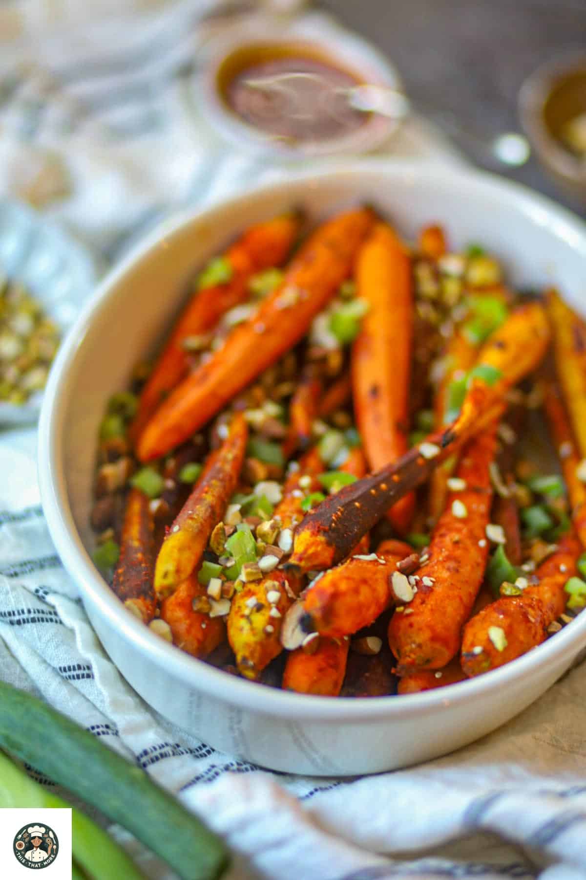 Air fryer roasted gochujang carrots in a white baking dish with nuts and scallions.