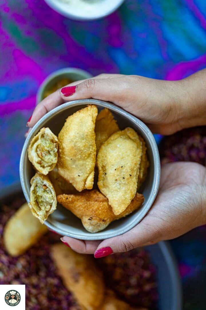 Holding the bowl filled with homemade mawa gujiya.