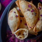 Image of Gujiya Recipe with coconut filling served in a black bowl for holi.