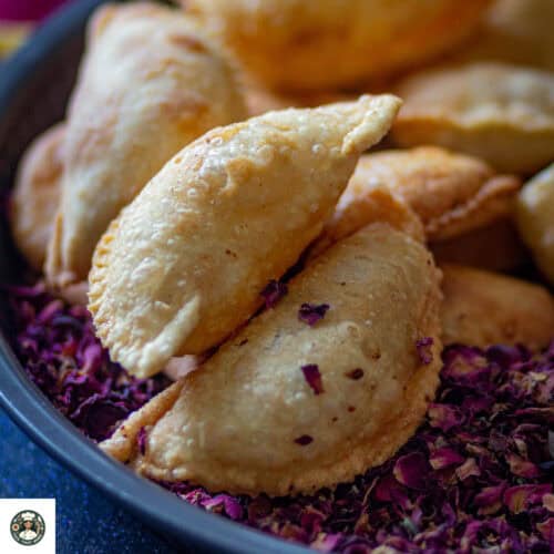 Image of closeup shot of gujiya recipe placed over rose petals.