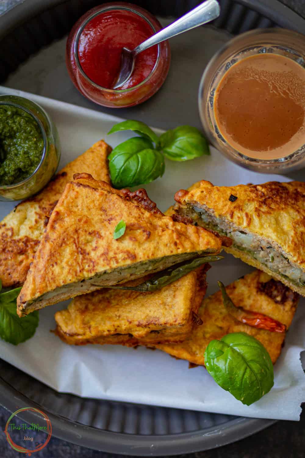 bread pakora garnished with some basil leaves on a white plate.