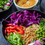 Noodles with veggies added in the mixing bowl.