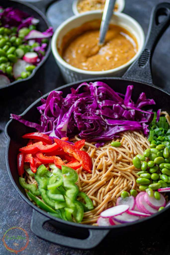 Noodles with veggies added in the mixing bowl.
