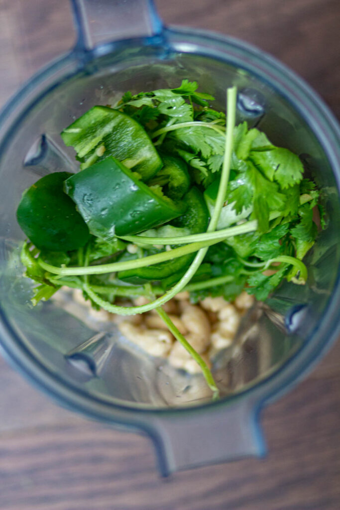make cream sauce by adding cashews, water, cilantro, jalapeno, and salt in a blender