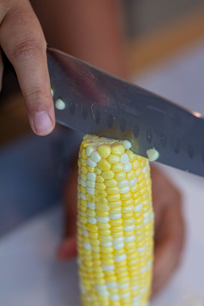 hold the corn vertically and slice the corn from the middle
