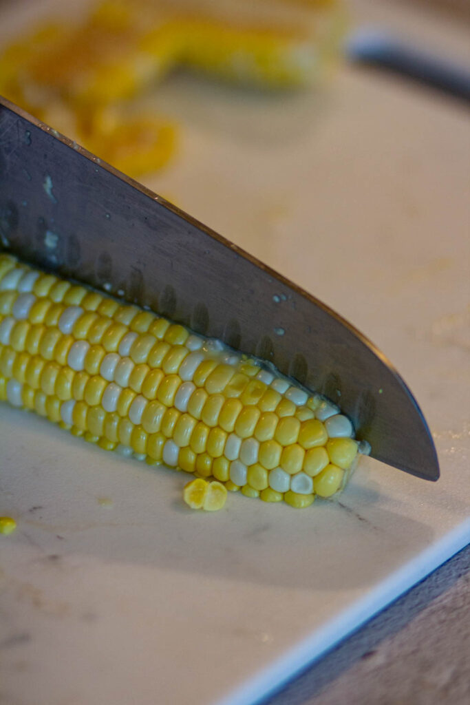 cut the half of the corn with the knife by placing them down on the cutting board