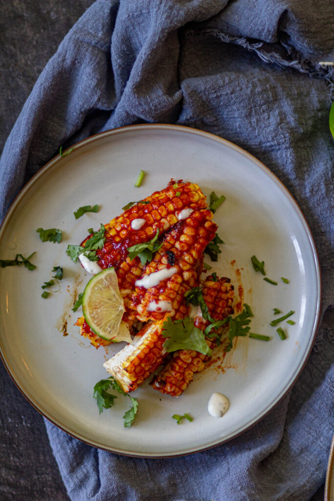 corn ribs on a serving plate with some cilantro & lemon