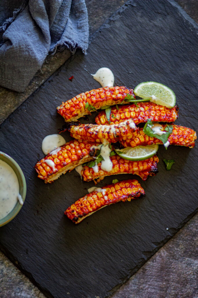 corn ribs on black cutting board with some ranch