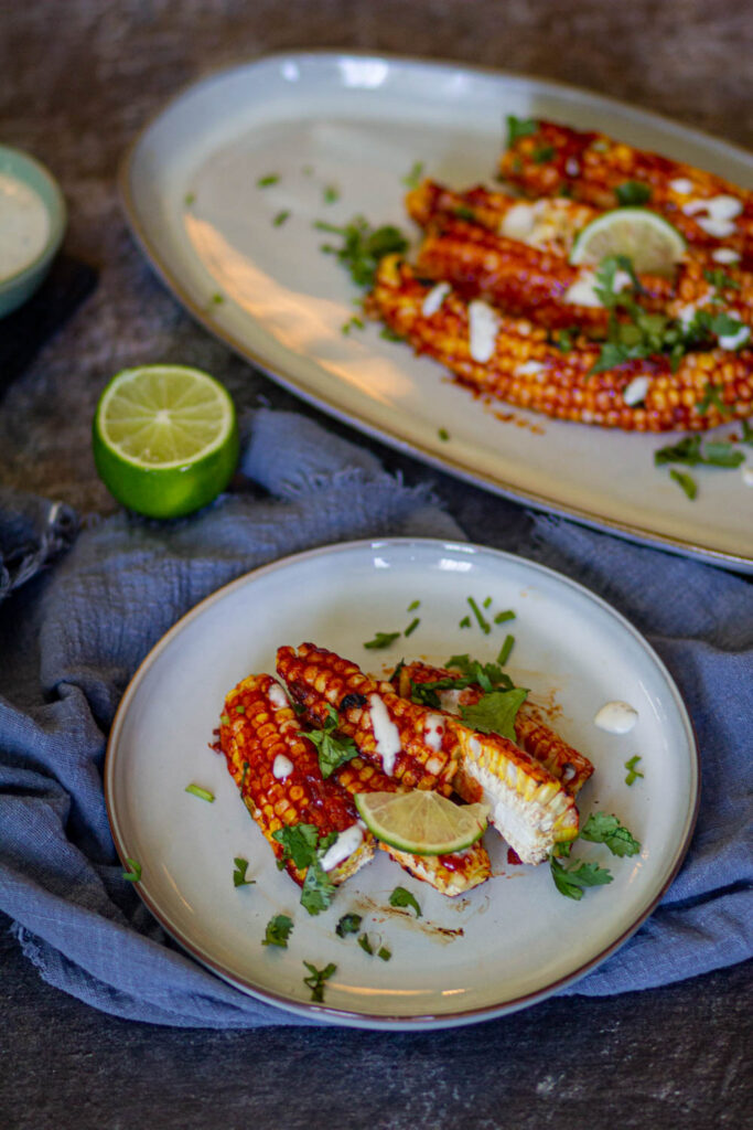 air fryer corn ribs on white plate with soem extra corn ribs on big plate in the playground