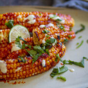 corn ribs in white plate with some cilantro and lemon
