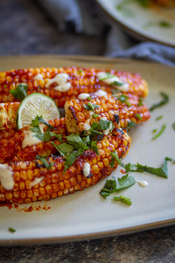 corn ribs in white plate with some cilantro and lemon