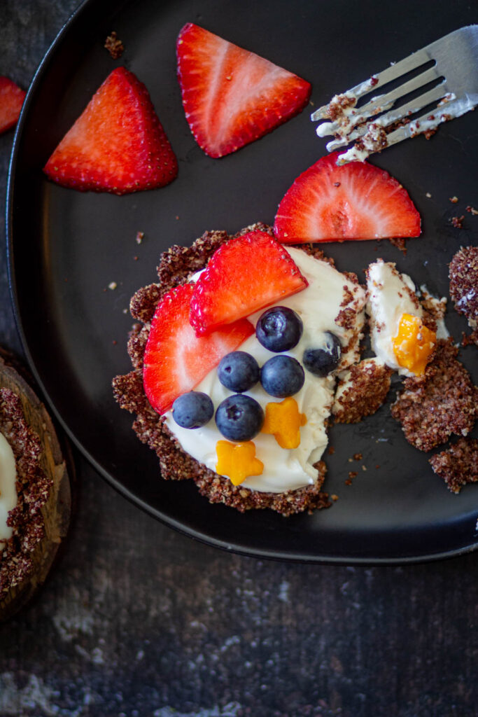 mini fruit tart on a black plate with fork
