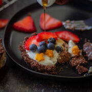 mini fruit tar on a black plate topped with blueberries and strawberries