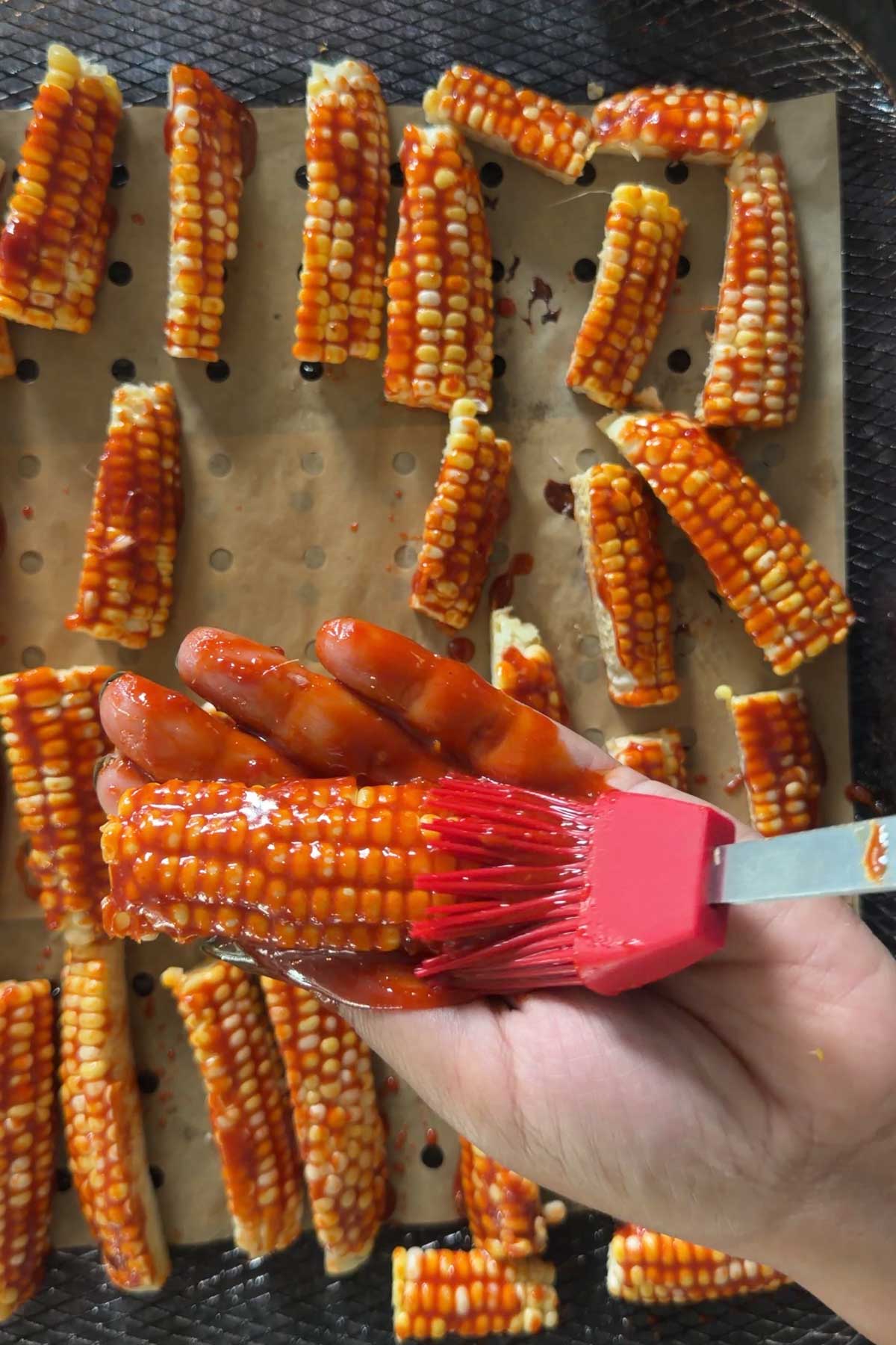 Brushing gochujang glaze over corn ribs before air frying.