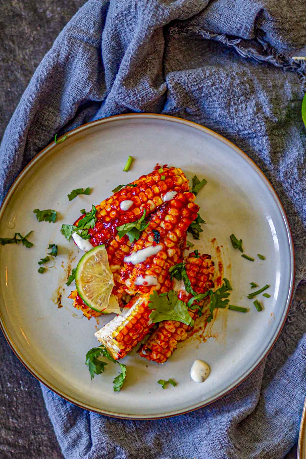 Spicy gochujang corn ribs garnished with cilantro and lime.