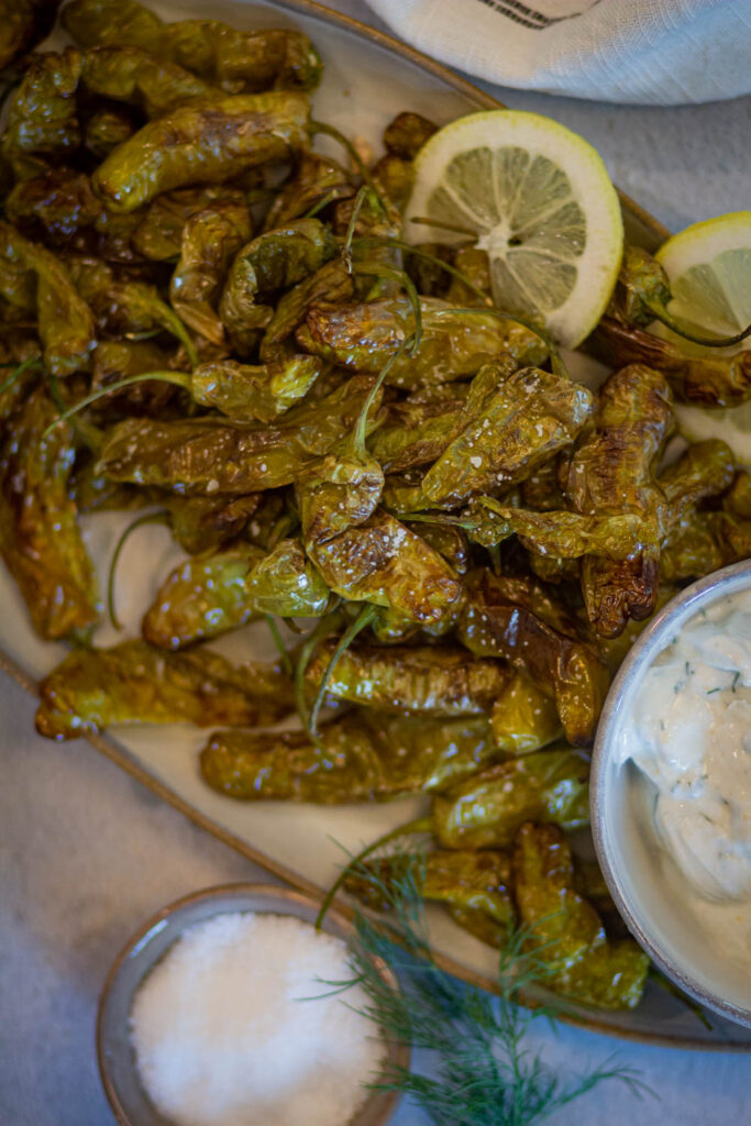 a closeup look of shisito peppers on white platter