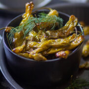 Shishito Peppers in a black bowl with dill on the top