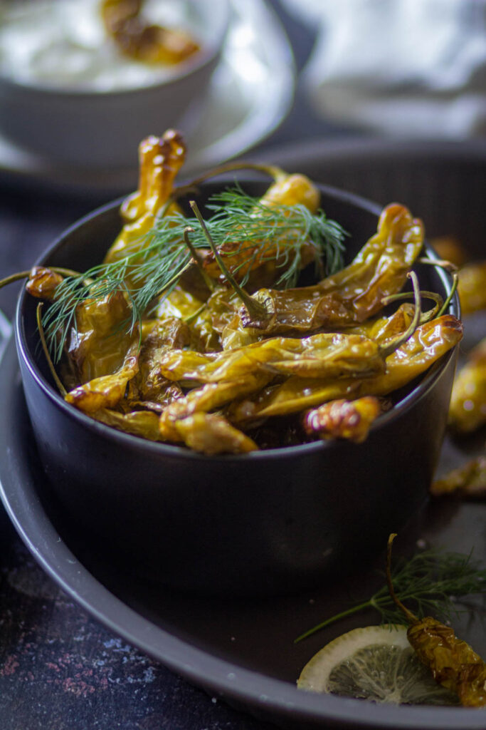 Shishito Peppers in a black bowl with dill on the top